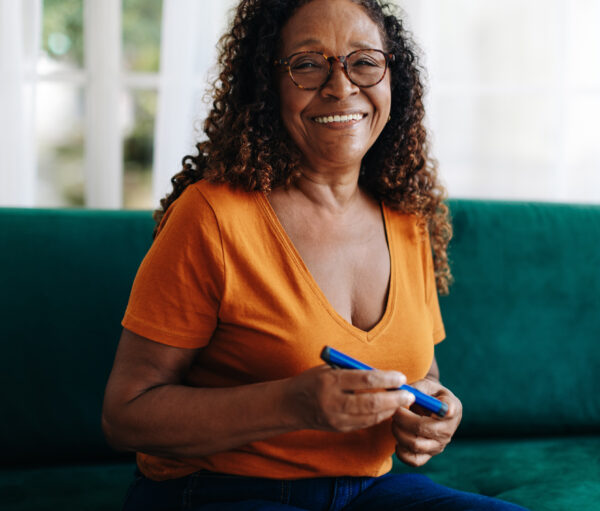 Black woman with diabetes uses a smart insulin pen to monitor and control her blood sugar levels, automatically recording the dose of insulin administered which helps manage the health condition.